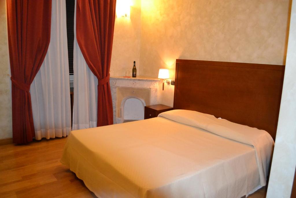 a bedroom with a white bed and a fireplace at Dipendenza Hotel Galileo in Rome