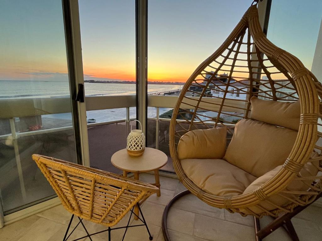une chaise pivotante et une table sur un balcon avec l'océan dans l'établissement Magnifique appartement pour 4 personnes face à la mer, à Saint-Gilles-Croix-de-Vie