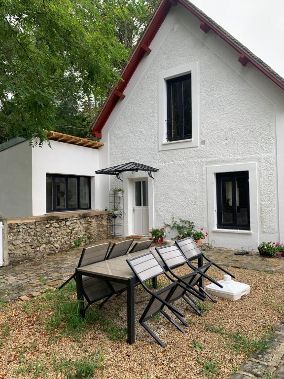 a picnic table and chairs in front of a house at Le Cottage du Domaine in Boissettes