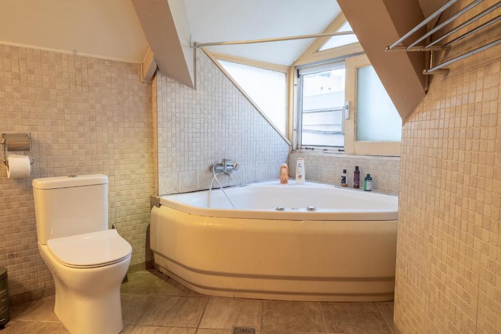 a bathroom with a tub and a toilet and a window at Neoclassical Mytilene - Vournazon 17 in Mytilini
