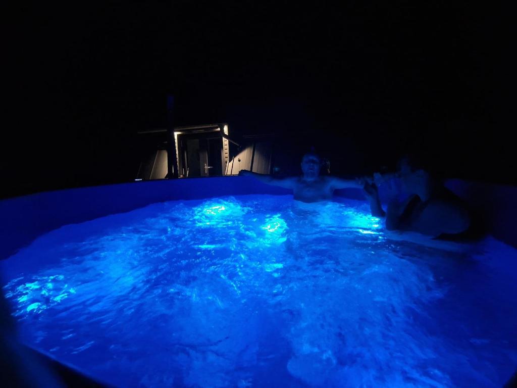 een man in een zwembad met blauwe lichten erin bij Hidden Chalet in Tarcău-Gheuca