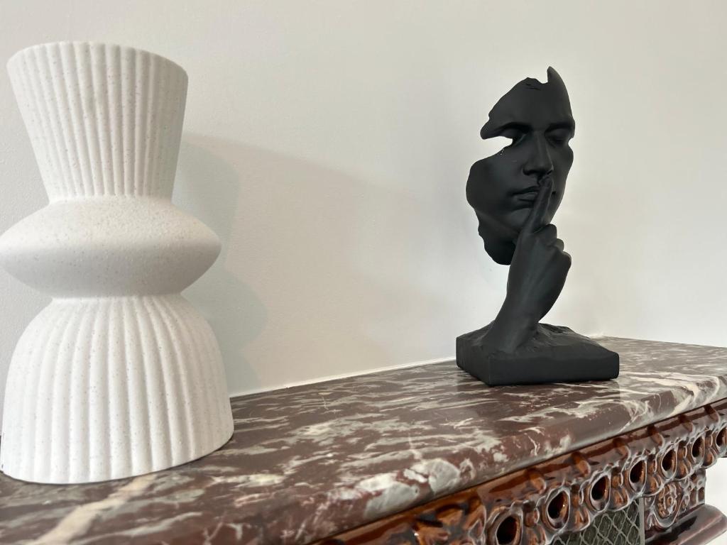 un buste d’une personne sur une table à côté d’une lampe dans l'établissement L apparté, à Beauvais