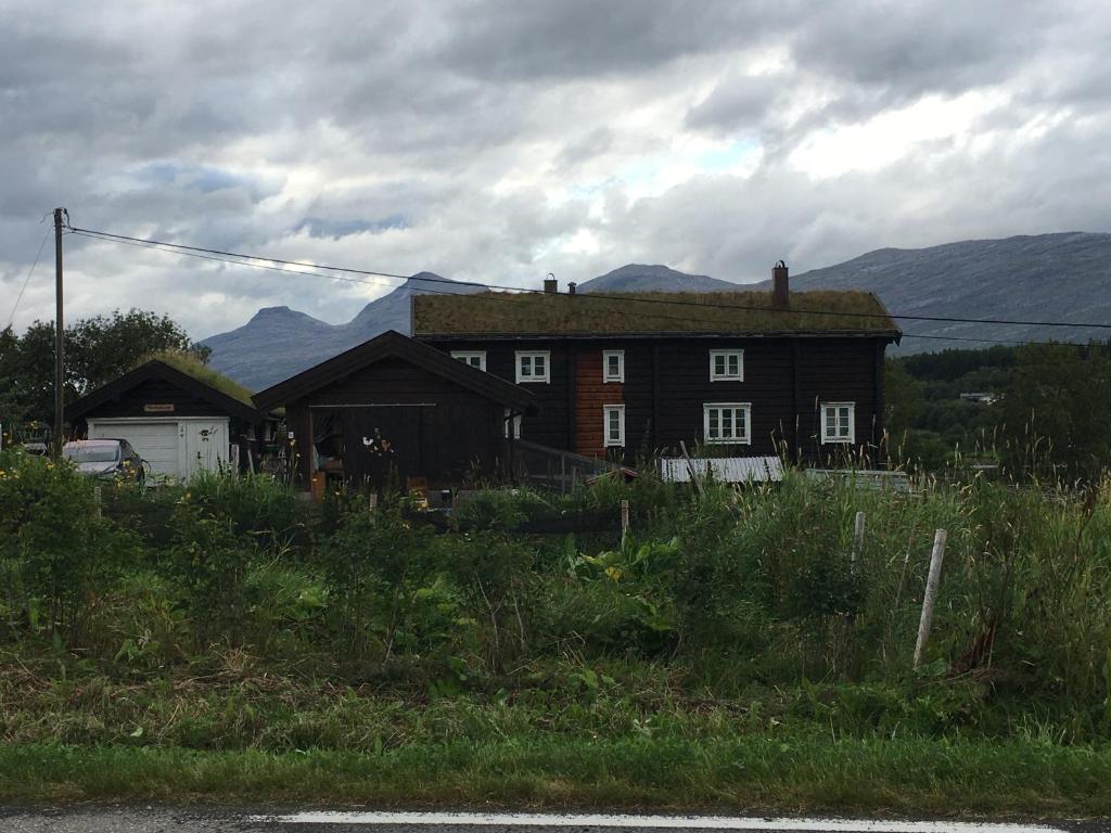 una casa antigua con montañas en el fondo en Hyggelig lite bosted ved sjøen, nær sentrum i Valnesfjord, en Stokkland
