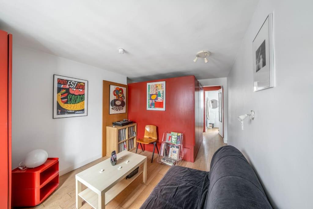 - un salon avec un canapé et un mur rouge dans l'établissement Appartement confortable dans le centre de Paris, à Paris