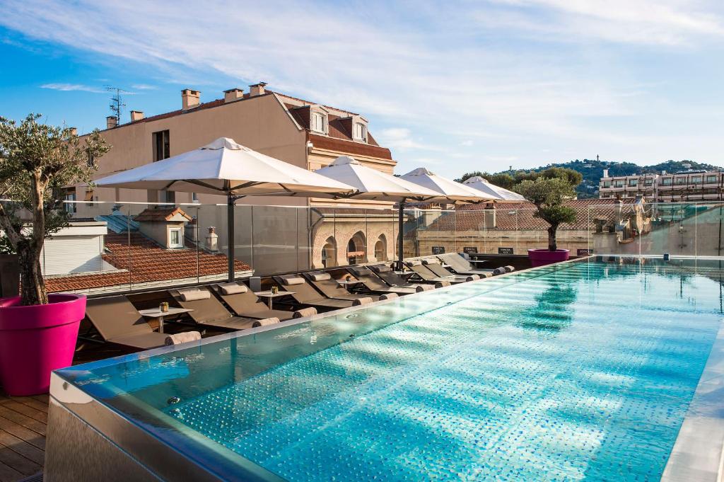 une piscine sur le toit d'un immeuble avec des chaises et des parasols dans l'établissement Five Seas Hotel Cannes, a Member of Design Hotels, à Cannes