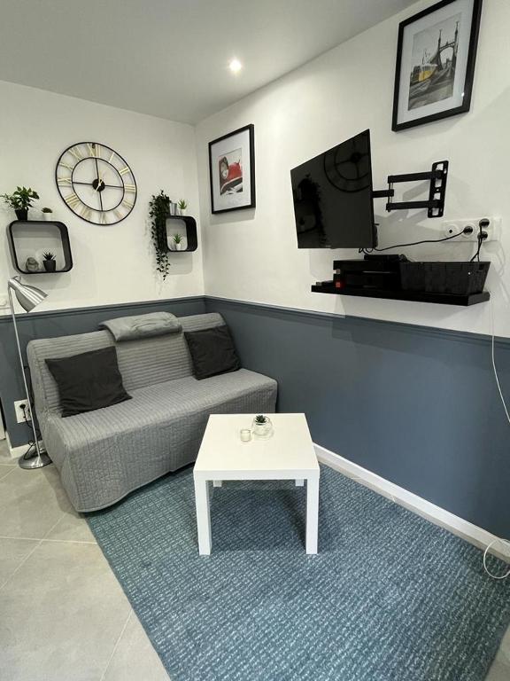 un salon avec un canapé, une télévision et une table dans l'établissement Studio Cosy à Fontenay le Fleury, à Fontenay-le-Fleury