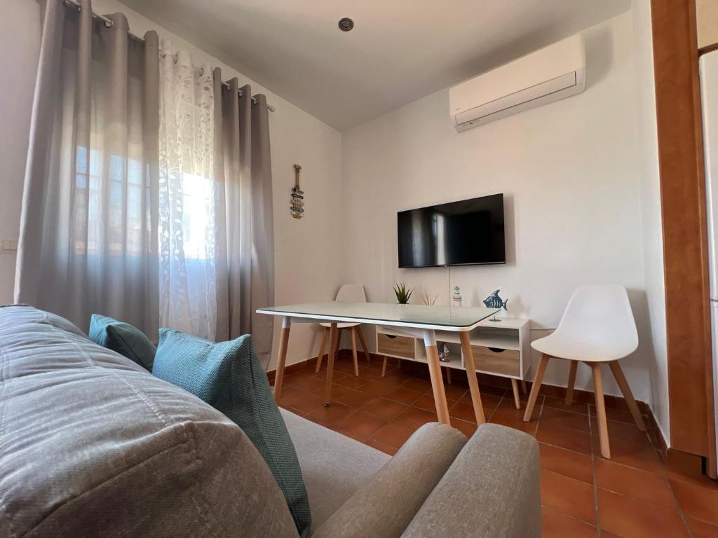 a living room with a bed and a table and a tv at Seaside Paradise Mazagon in Mazagón