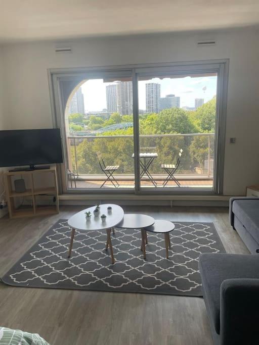 un salon avec une table et une grande fenêtre dans l'établissement Tour Eiffel vue seine avec terrasse, à Paris