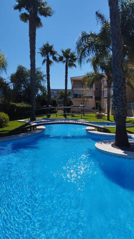 a swimming pool with palm trees in a resort at Apartamento Familiar Jávea en Planta Baja in Jávea