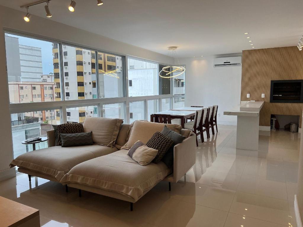 a living room with a couch and a kitchen and a table at 3 Suítes com Vista pro Mar em Balneário Camboriú! in Balneário Camboriú