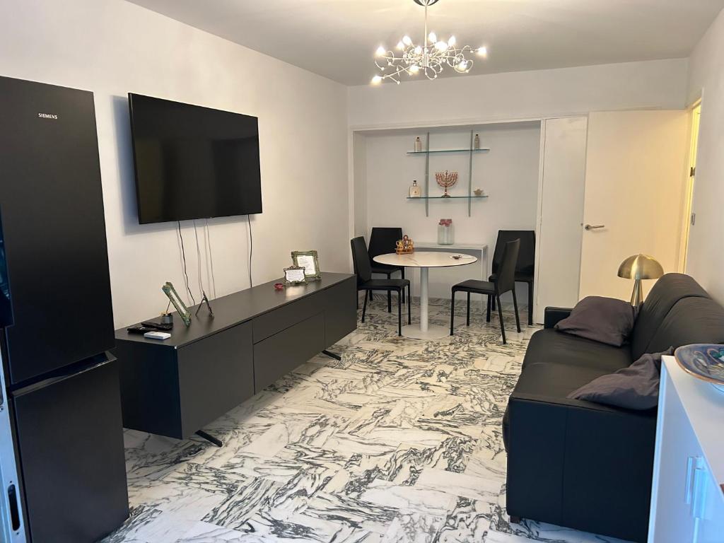 un salon avec un canapé, une télévision et une table dans l'établissement Appartement T2 bord de mer, à Cannes