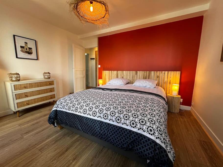 a bedroom with a large bed with a red wall at Appartement Gordon Smith en plein centre - 2 personnes in Sainte-Mère-Église