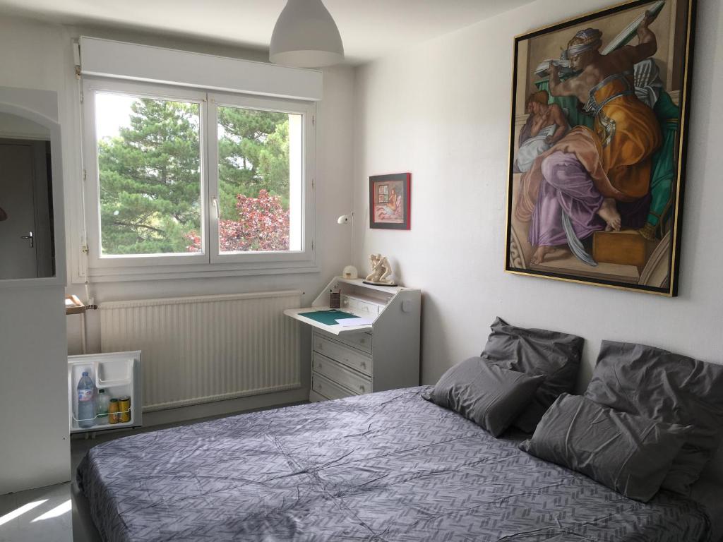 a bedroom with a bed and a painting on the wall at Bed and Breakfast Nantes au calme proche aéroport, gare et centre-ville in Saint-Sébastien-sur-Loire