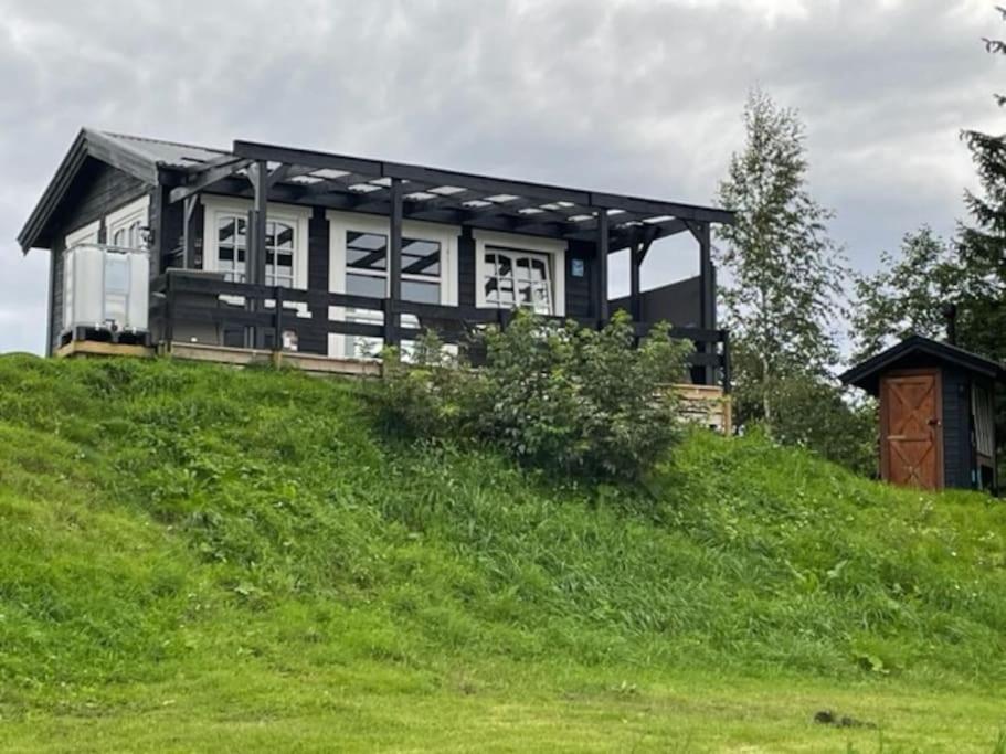 a house sitting on top of a green hill at Badehuset, Harmoni, med privat strand in Hemnes
