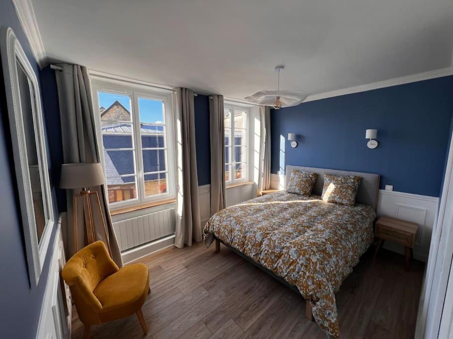 a bedroom with blue walls and a bed and a chair at Maison pour 10 personnes max en plein centre de Ste Mère Eglise in Sainte-Mère-Église