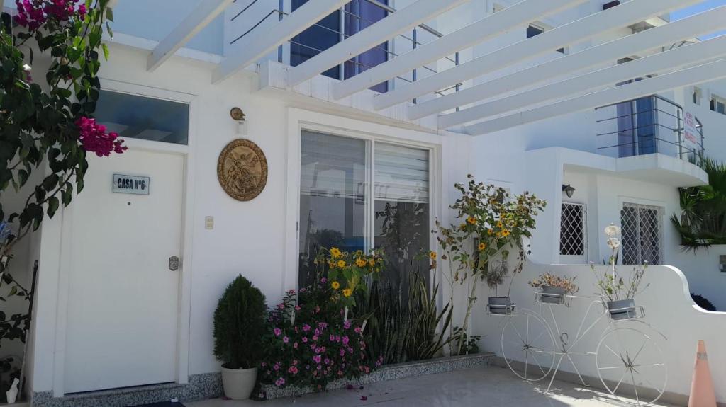 a white house with flowers on the porch at Ecusuites Playas House VI Resort Altamarll Piscina Playa in Playas