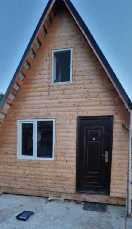 a log cabin with a black door and two windows at Cabană la LERI in Icloda