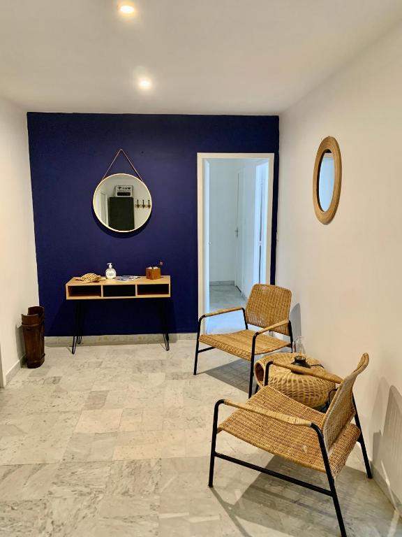 Cette chambre est dotée d'un mur bleu avec un miroir et des chaises. dans l'établissement Cosy flat 2 chambres, à Saint-Étienne