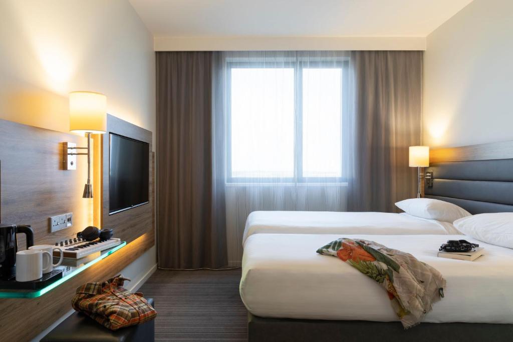 a hotel room with two beds and a television at Moxy Aberdeen Airport in Dyce