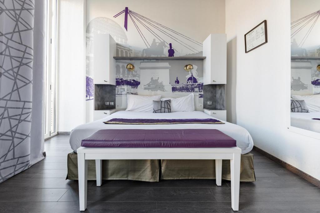 a white bedroom with a large bed with purple sheets at Lagrange Aparthotel Lyon Lumière in Lyon