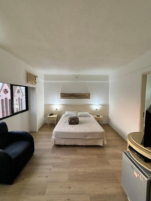 a bedroom with a bed and a couch and a television at Hotel Borges Lagoa Ibirapuera com garagem grátis 912 in Sao Paulo
