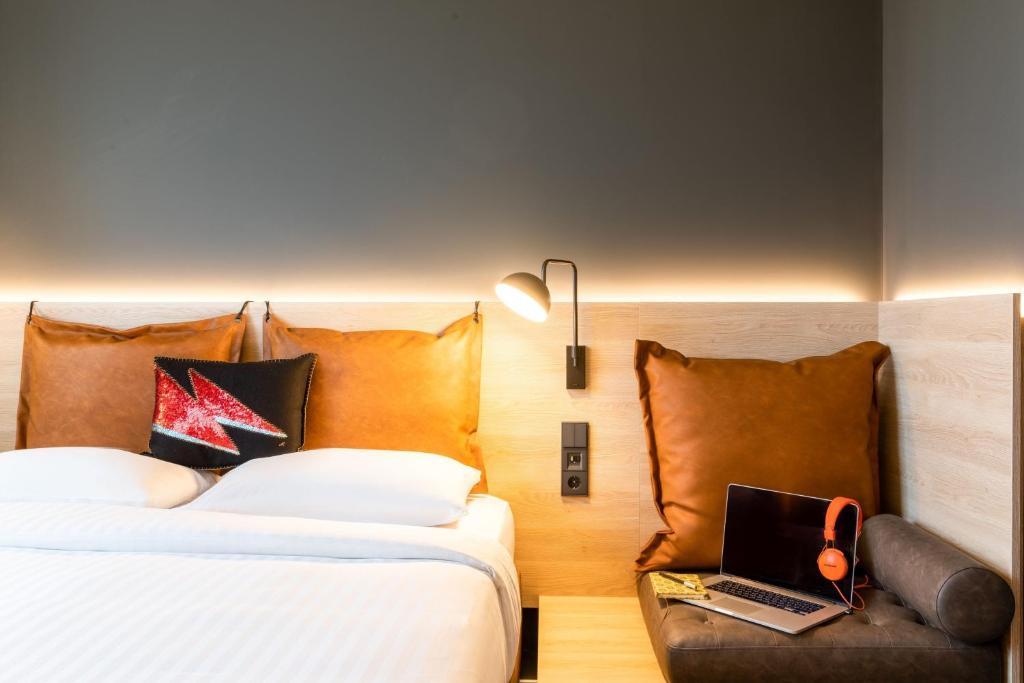 a bedroom with two beds and a laptop on a chair at Moxy Berlin Airport in Schönefeld