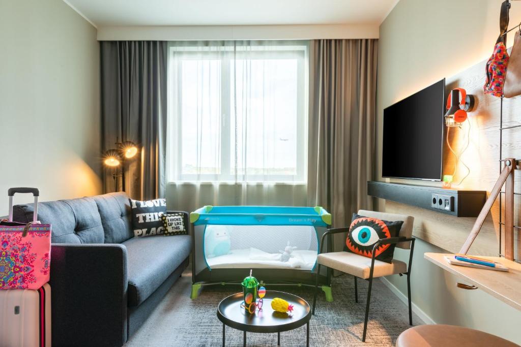a living room with a couch and a tv at Moxy Berlin Airport in Schönefeld