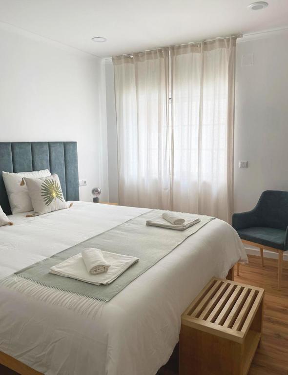 a bedroom with a large white bed with a blue chair at Lugar da Praia - Consolação - Peniche in Peniche