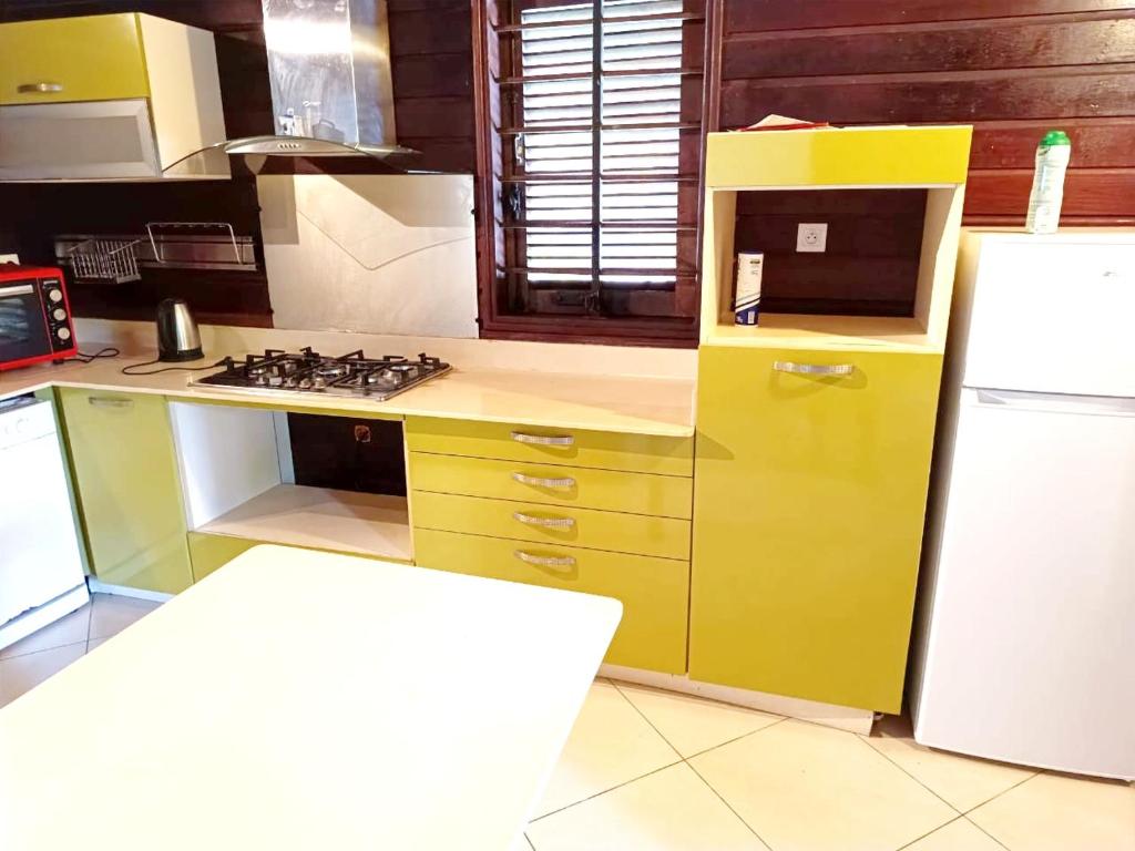a kitchen with a yellow refrigerator and a stove at Kreyolita in Saint-Laurent du Maroni