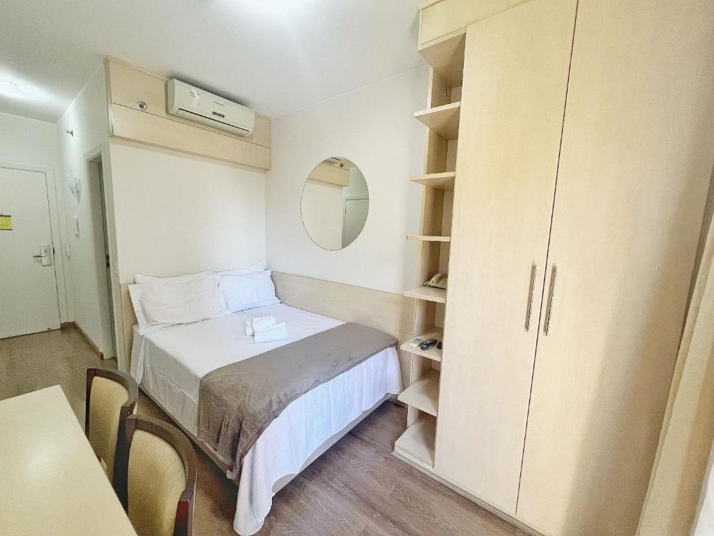 Habitación pequeña con cama y armario en ENB | Ótima Suite hotel em SCS, próx a GM, en São Caetano do Sul