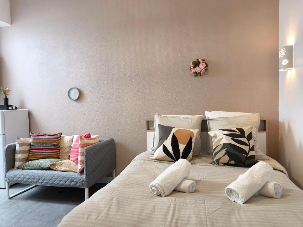a bedroom with a bed with pillows and a chair at Magnifique Studio Douillet in Le Mans