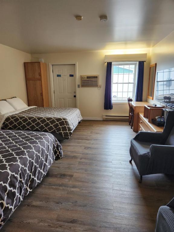 a hotel room with two beds and a desk at Covered Bridge Inn & Suites in Sussex