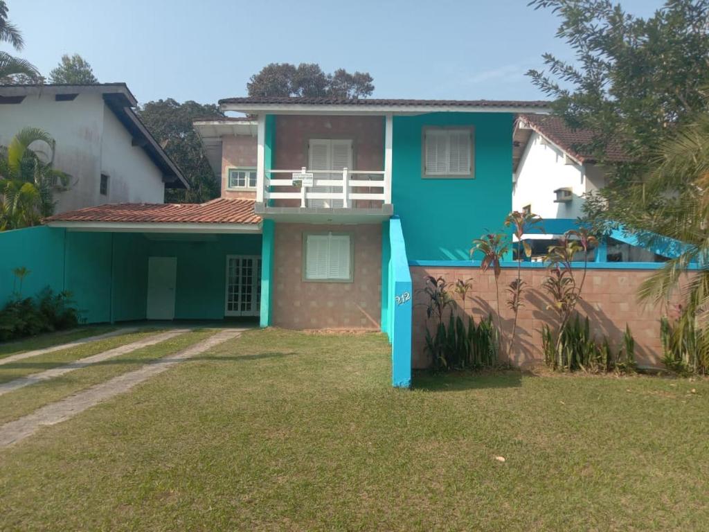 a blue house with a balcony in a yard at Paraíso de Verão - Disfrute final de semana em Casa Exclusiva com piscina, sinuca e churrasqueira Aluguel para temporada em Riviera de São Lourenço in Bertioga