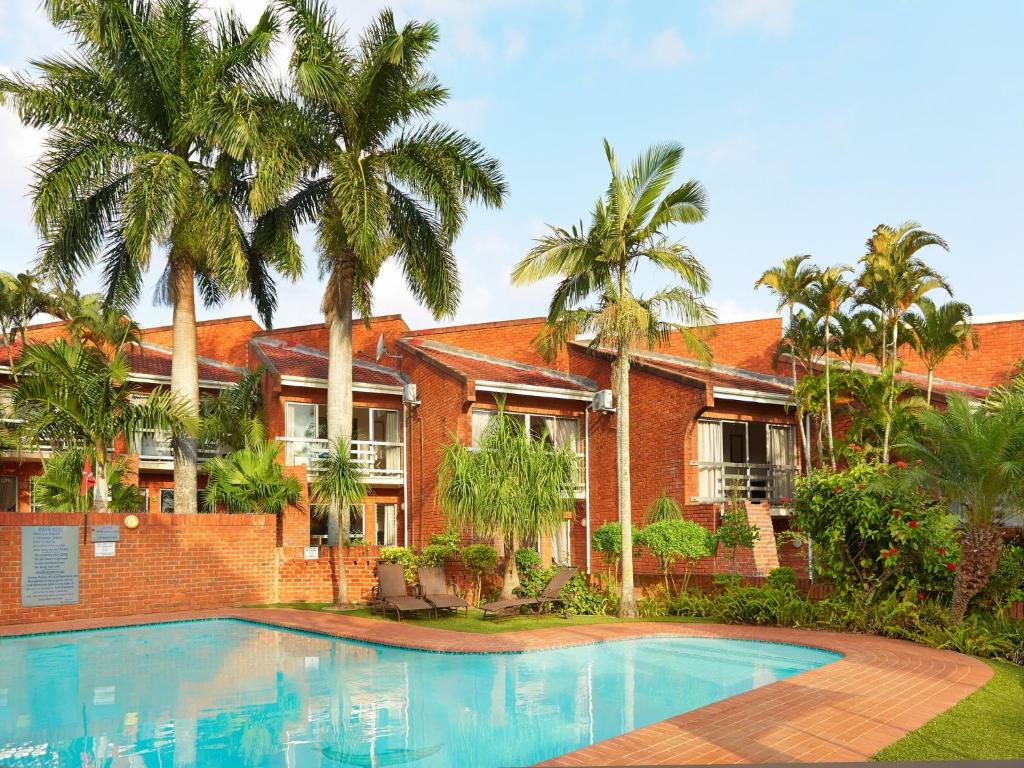 a house with a swimming pool and palm trees at Perna Perna Lodge St Lucia in St Lucia