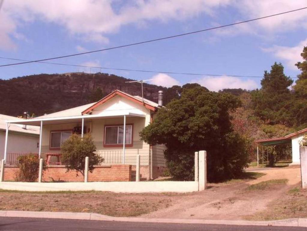 a white house with a mountain in the background at Kandos Cottage in Kandos