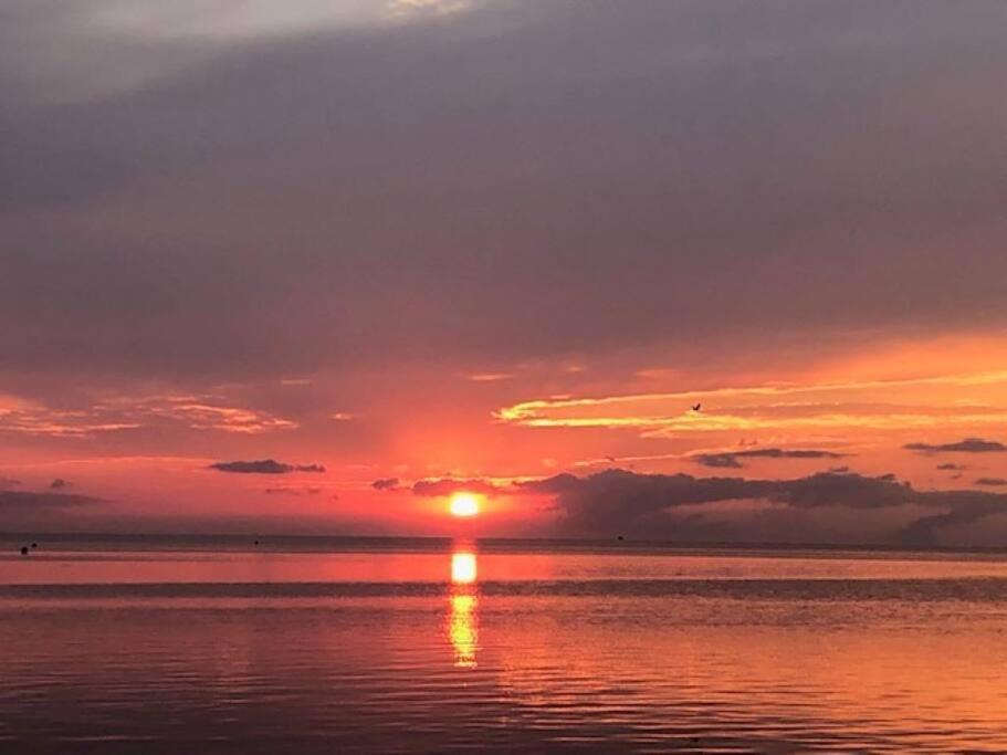 um pôr do sol sobre o oceano com o sol se pondo em Captain's Quarters em Avon