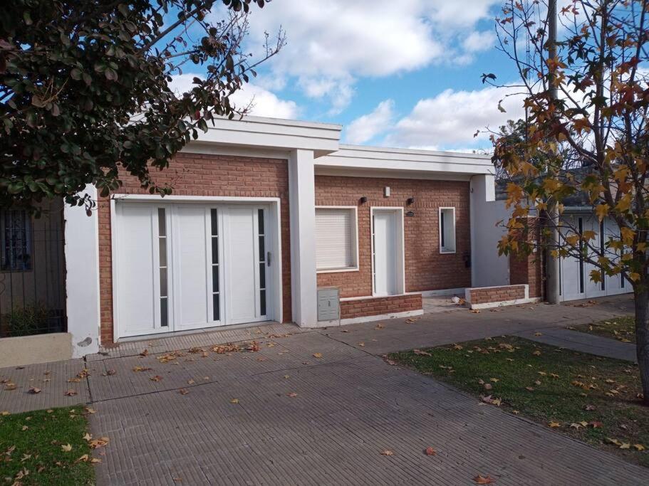 Una casa de ladrillo con puertas blancas de garaje. en comodidad y seguridad, en Ciudad Evita