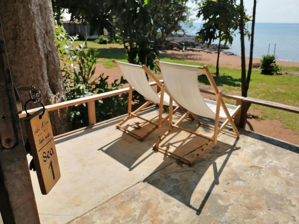 two white chairs sitting on a porch with the beach at Villa Allure Koh Mak in Ko Mak
