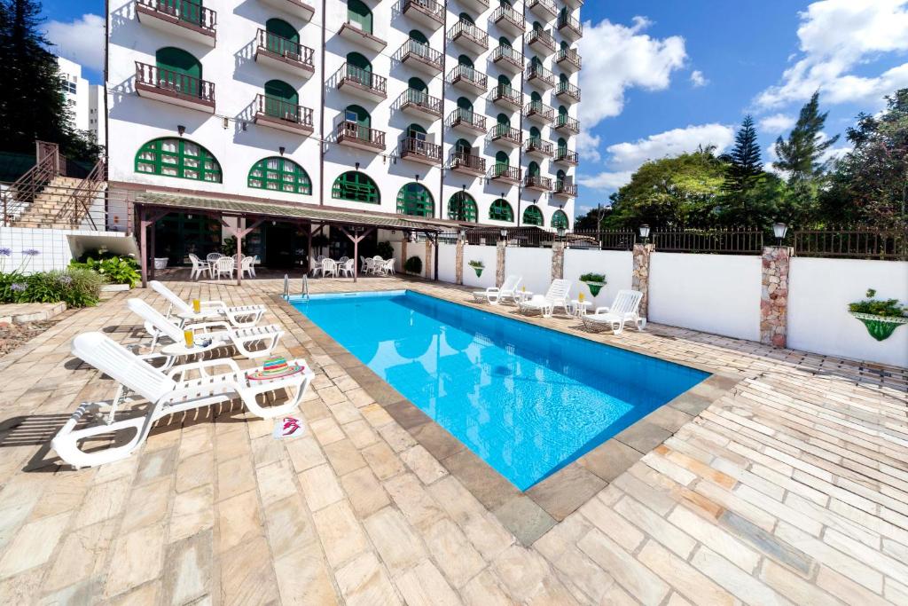 um hotel com piscina e cadeiras e um edifício em Hotel Tannenhof em Joinville