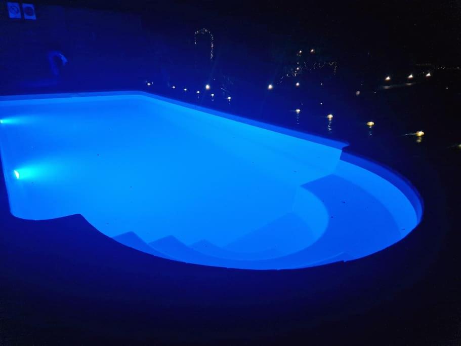 a blue swimming pool lit up at night at Domek w drzewach Ostoja in Krzesimów