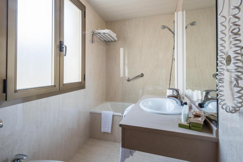 uma casa de banho com um lavatório e uma banheira em Riu Nere Mountain Hotel em Vielha