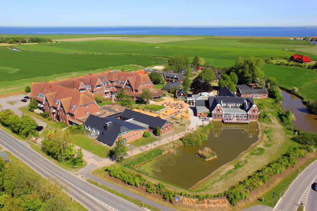 - une vue aérienne sur une grande maison avec un lac dans l'établissement DJH Resort Neuharlingersiel, à Neuharlingersiel