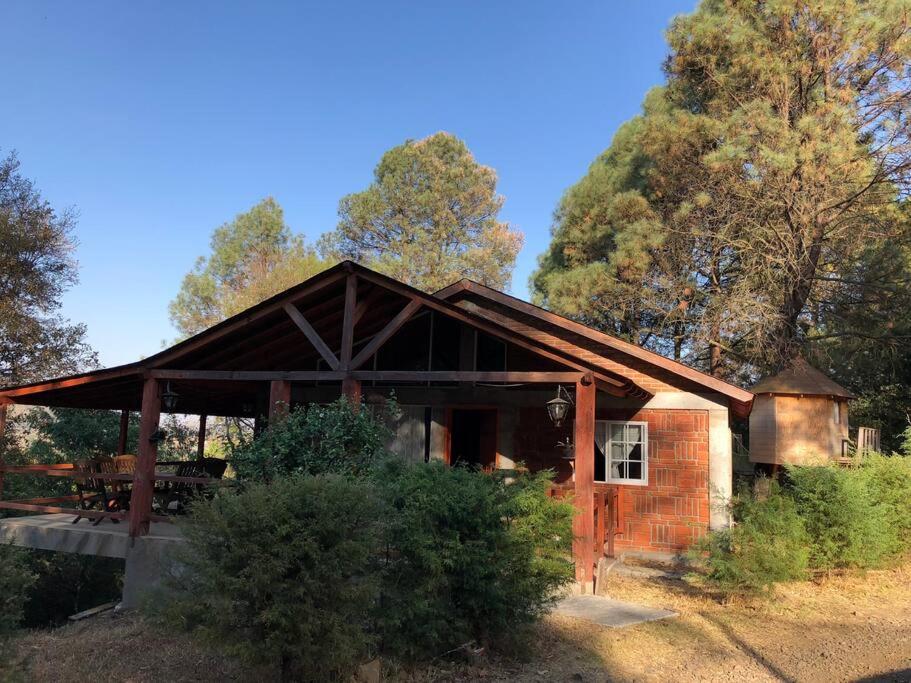 a small brick building with a porch and trees at Hermosa Cabaña en bosque muy cerca Patzcuaro in Tupátaro