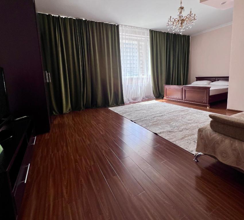 a living room with a bed and a large wooden floor at 7 Очень теплая и уютная квартира возле Байтерека для 1-4 чел кровать и диван in Astana