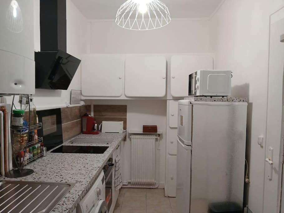 La cuisine est équipée d'un réfrigérateur blanc et d'un four micro-ondes. dans l'établissement La petite maison avec patio dans la cour, à Aubervilliers