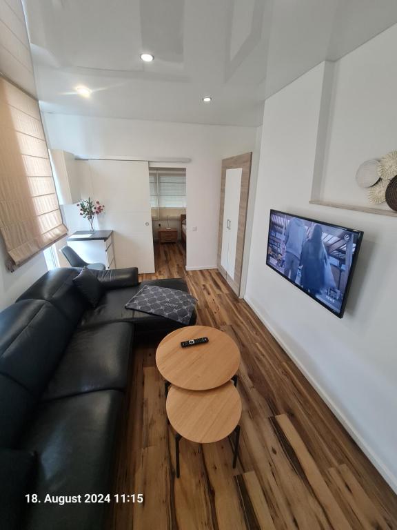 ein Wohnzimmer mit einer schwarzen Ledercouch und einem Tisch in der Unterkunft Handwerkerwohnung-Monteurunterkunft in Darmstadt