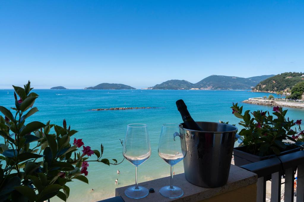 two wine glasses and a bucket on a balcony with the ocean at Hotel Florida Lerici in Lerici