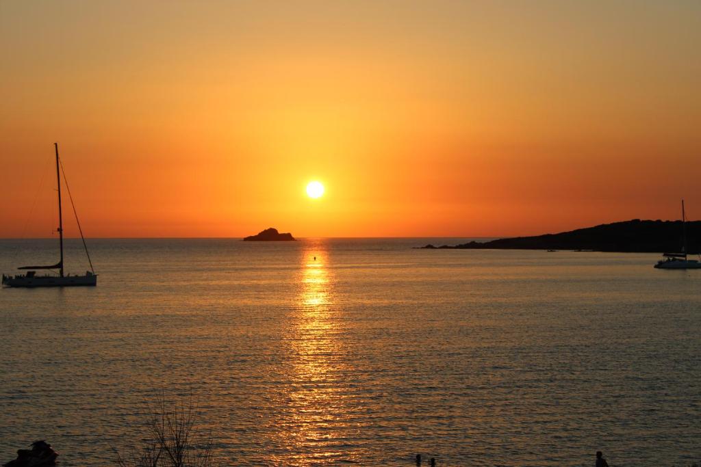 - un coucher de soleil sur l'océan avec un bateau dans l'eau dans l'établissement A Rundinella, à Grosseto-Prugna