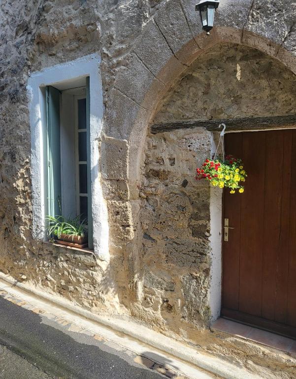 - un bâtiment en pierre avec une porte et un panier de fleurs dans l'établissement Maison Flamingo, à Saint-Geniès-de-Fontedit