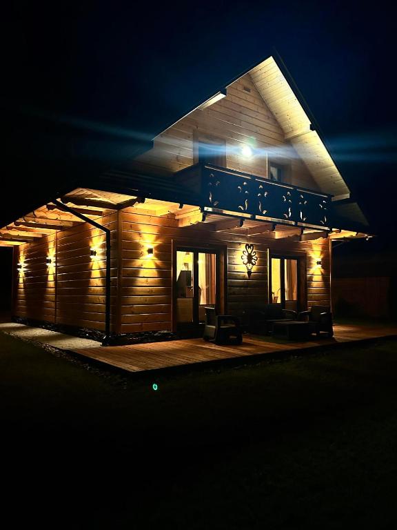a small wooden house at night with lights at Leśne Zacisze & Spa na wyłączność in Lubień